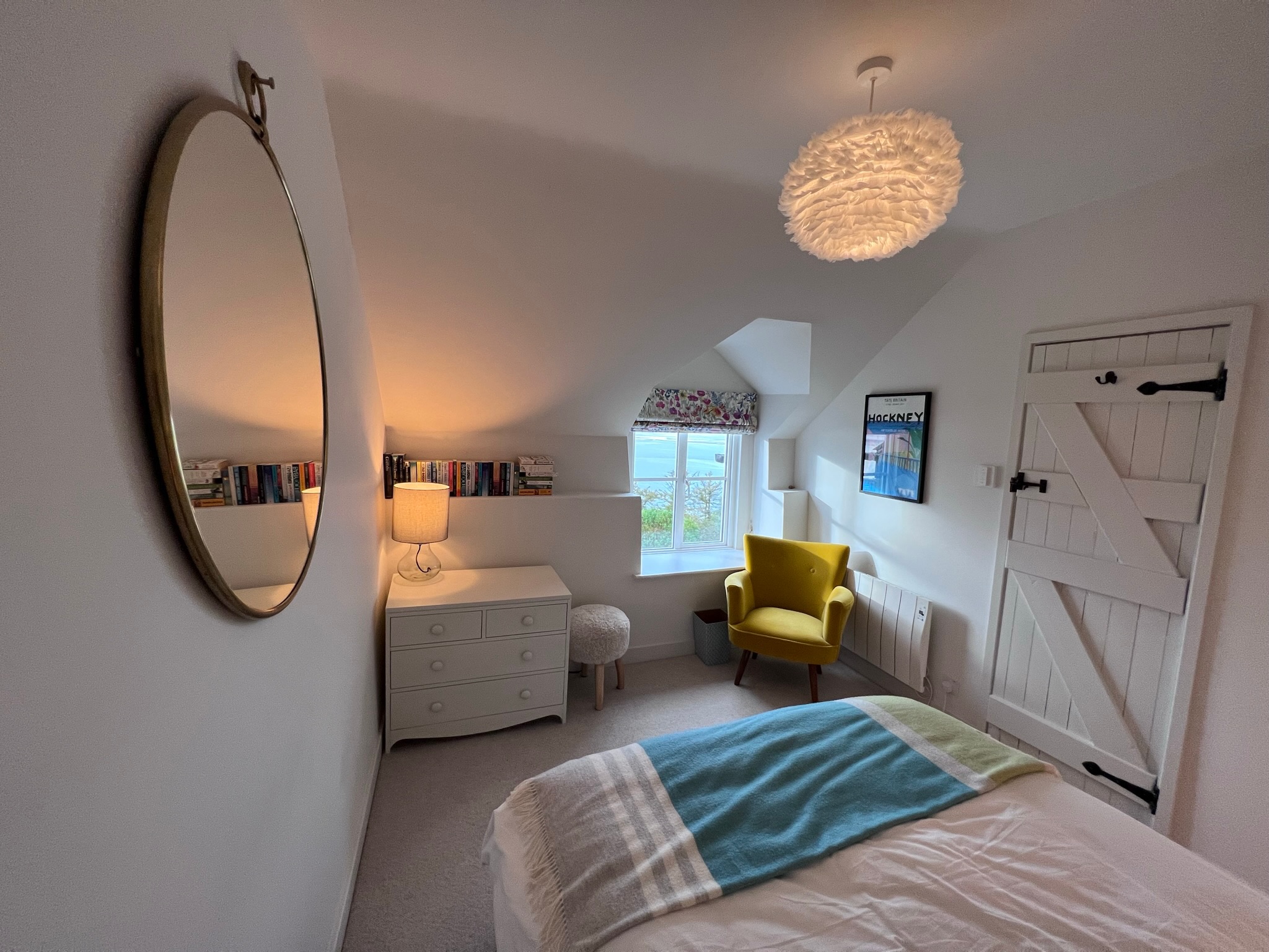 Attic bedroom with yellow chair and feather pendant light